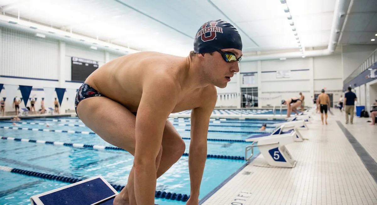 سباح شاب ينطلق بسرعة من حائط الحوض في حارة سباحة مخصصة لتدريبات السرعة والرشاقة